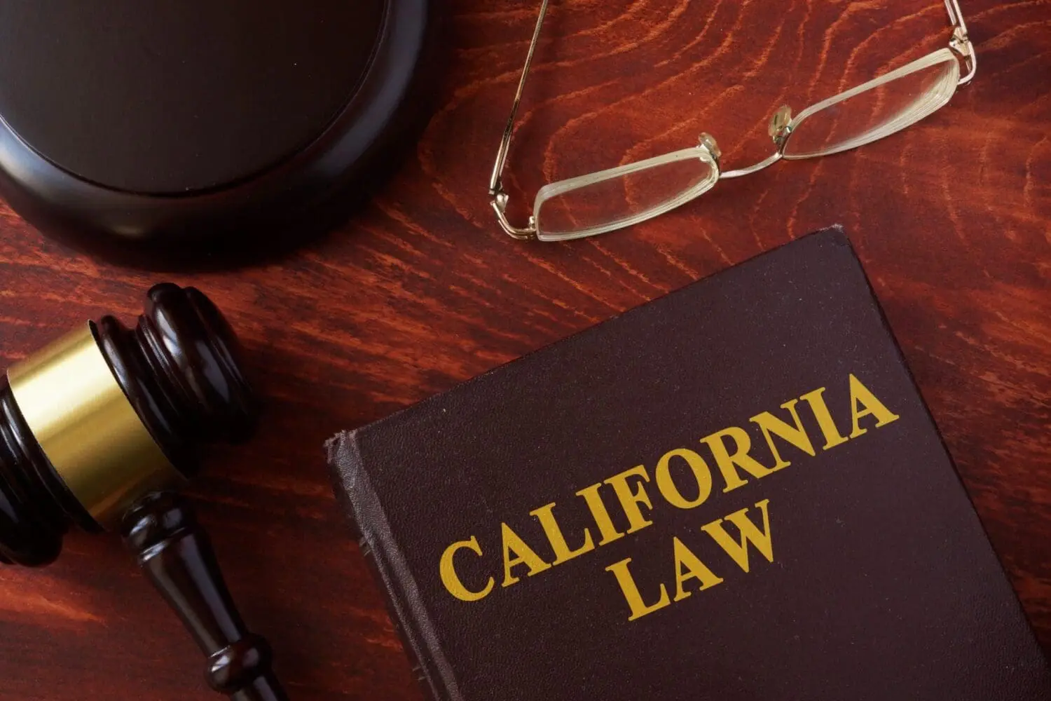 Adherent (formerly Compliance & Risks). A gavel, gavel block, eyeglasses, and a book titled 'CALIFORNIA LAW' on a wooden surface.