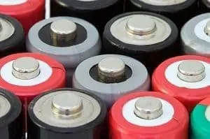 Top-down view of multiple cylindrical batteries in red, black, and grey, showing their silver positive terminals.