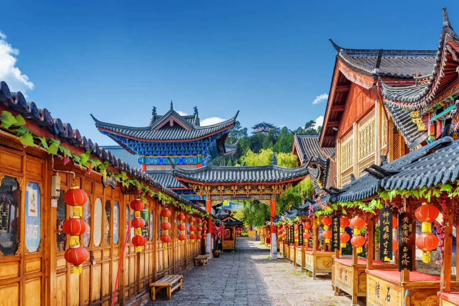 Adherent (formerly Compliance & Risks). A traditional Chinese street with wooden buildings, red lanterns, and market stalls. An ornate temple is visible in the background on a green hill under a blue sky.