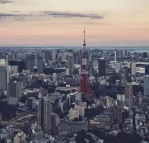 Aerial view of Tokyo cityscape with the red and white Tokyo Tower prominent in the center, under a twilight sky.