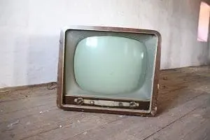Adherent (formerly Compliance & Risks). An old, vintage television with a dark wooden casing and a curved, light-colored screen sits on a wooden floor.