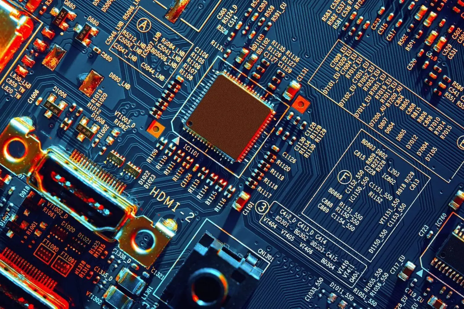 Adherent (formerly Compliance & Risks). A detailed, illuminated close-up of a dark blue circuit board with various electronic components, including a central microchip and an HDMI port, glowing with orange and red light.