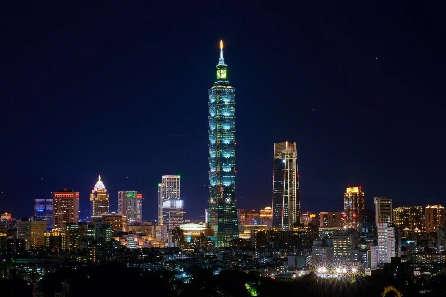 Adherent (formerly Compliance & Risks). Taipei 101 skyscraper illuminated in blue and green at night, surrounded by a glowing city skyline.