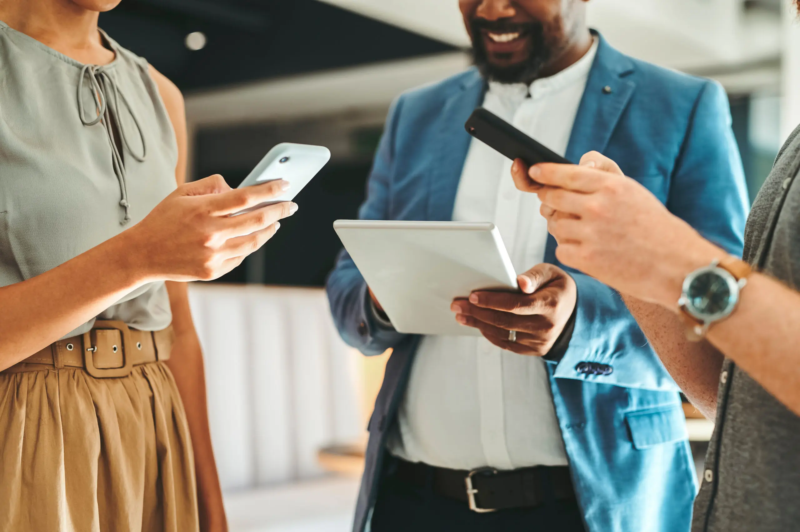 Adherent (formerly Compliance & Risks). Three people, partially visible, holding and looking at their smartphones and a tablet in an indoor setting.