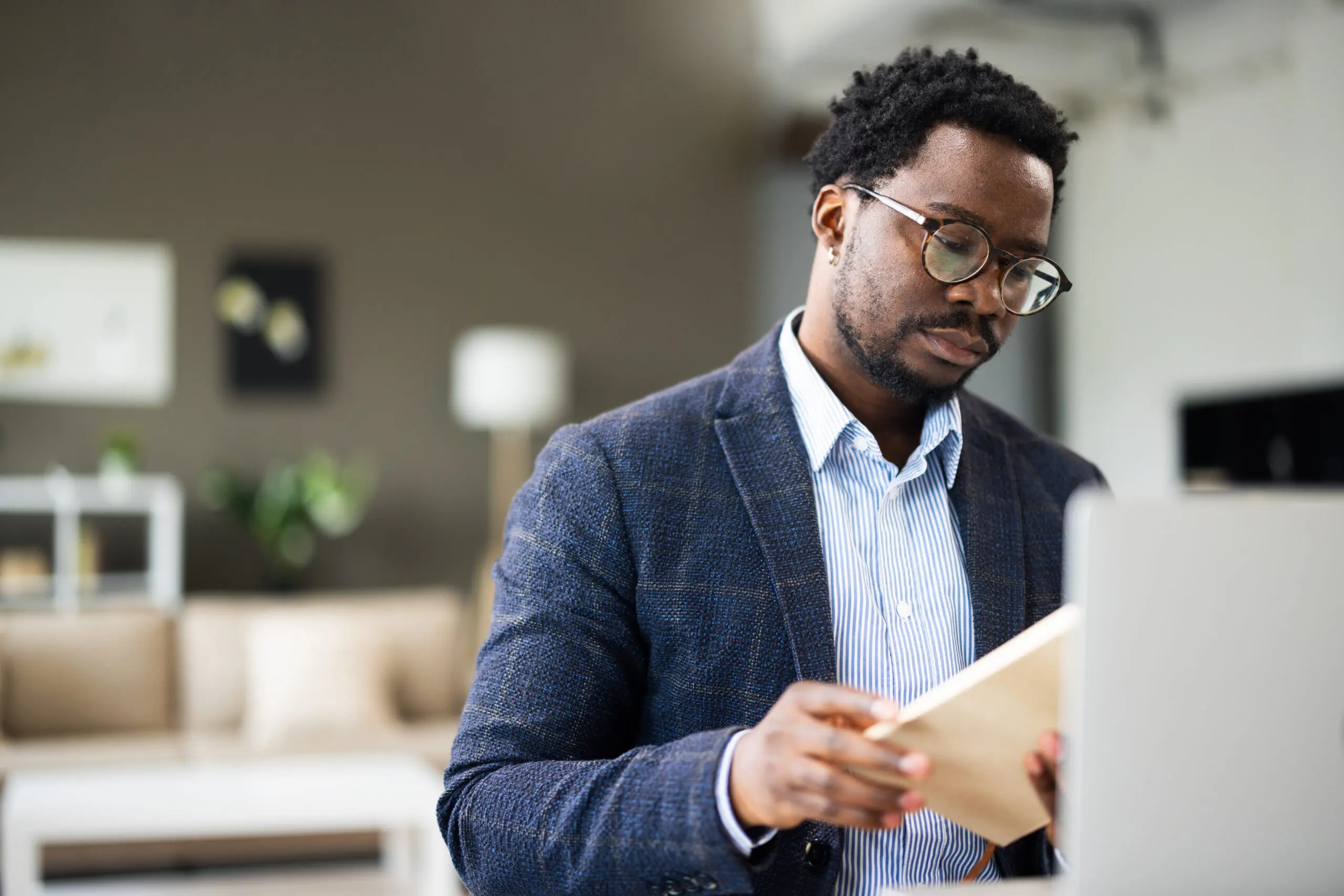 Adherent (formerly Compliance & Risks). A man with glasses and a blazer reads a book at a desk, with a laptop nearby.