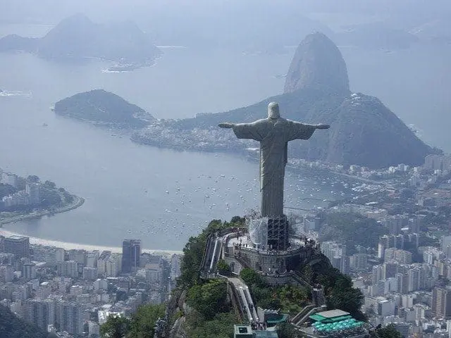 Aerial view of Christ the Redeemer statue overlooking Rio de Janeiro city, Guanabara Bay, and Sugarloaf Mountain.