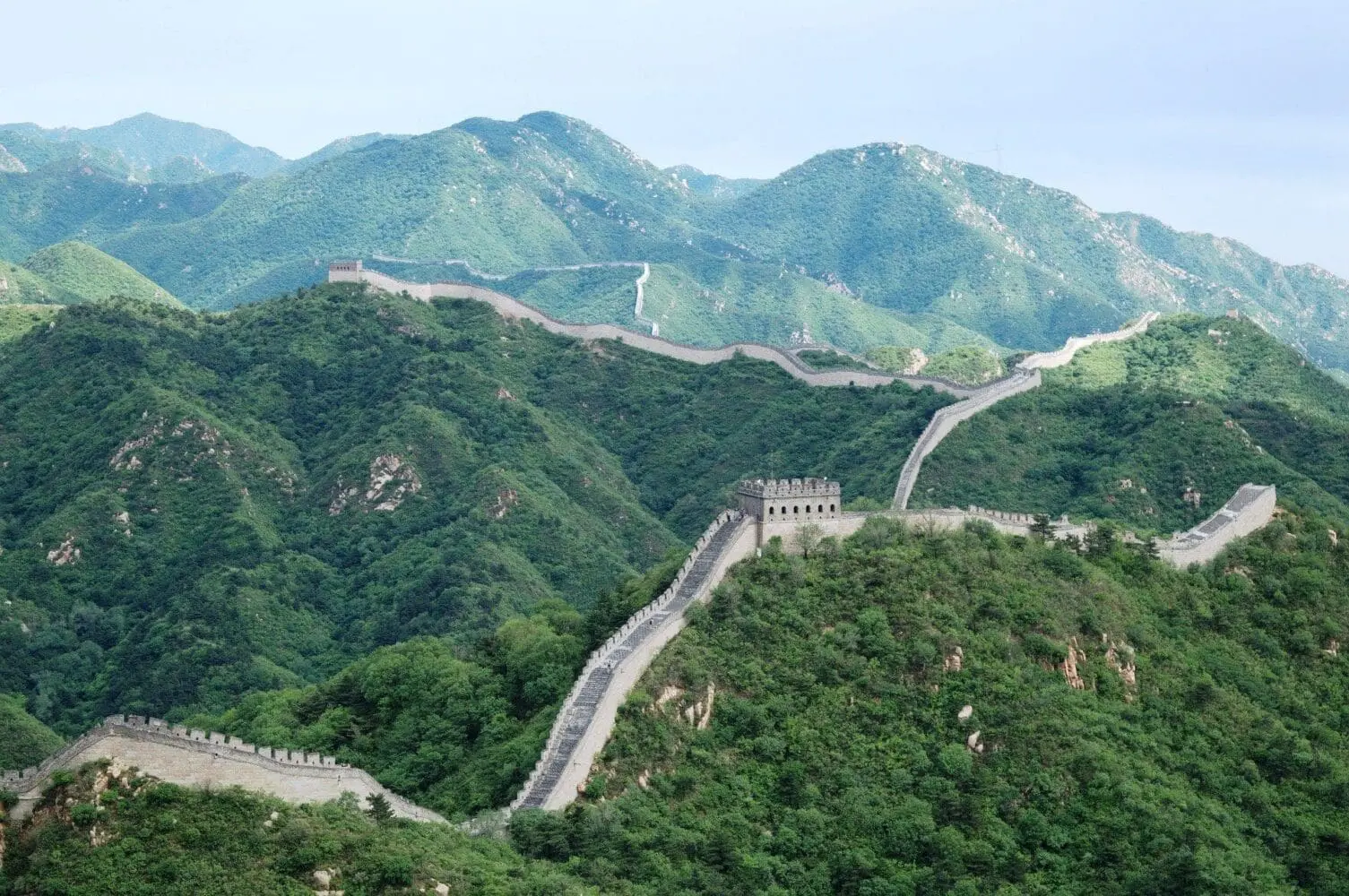Adherent (formerly Compliance & Risks). The Great Wall of China stretches across a series of green, forested mountains with watchtowers, under a clear sky.
