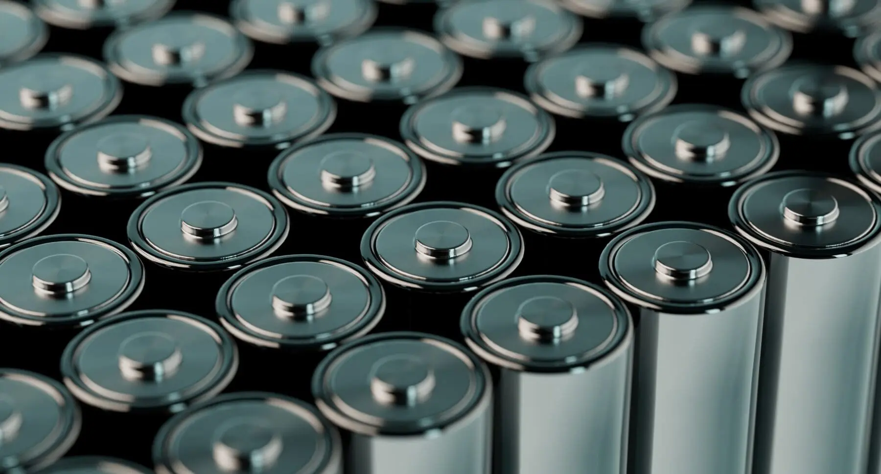 Adherent (formerly Compliance & Risks). A close-up view of many silver cylindrical batteries with metallic tops arranged in rows on a dark background.