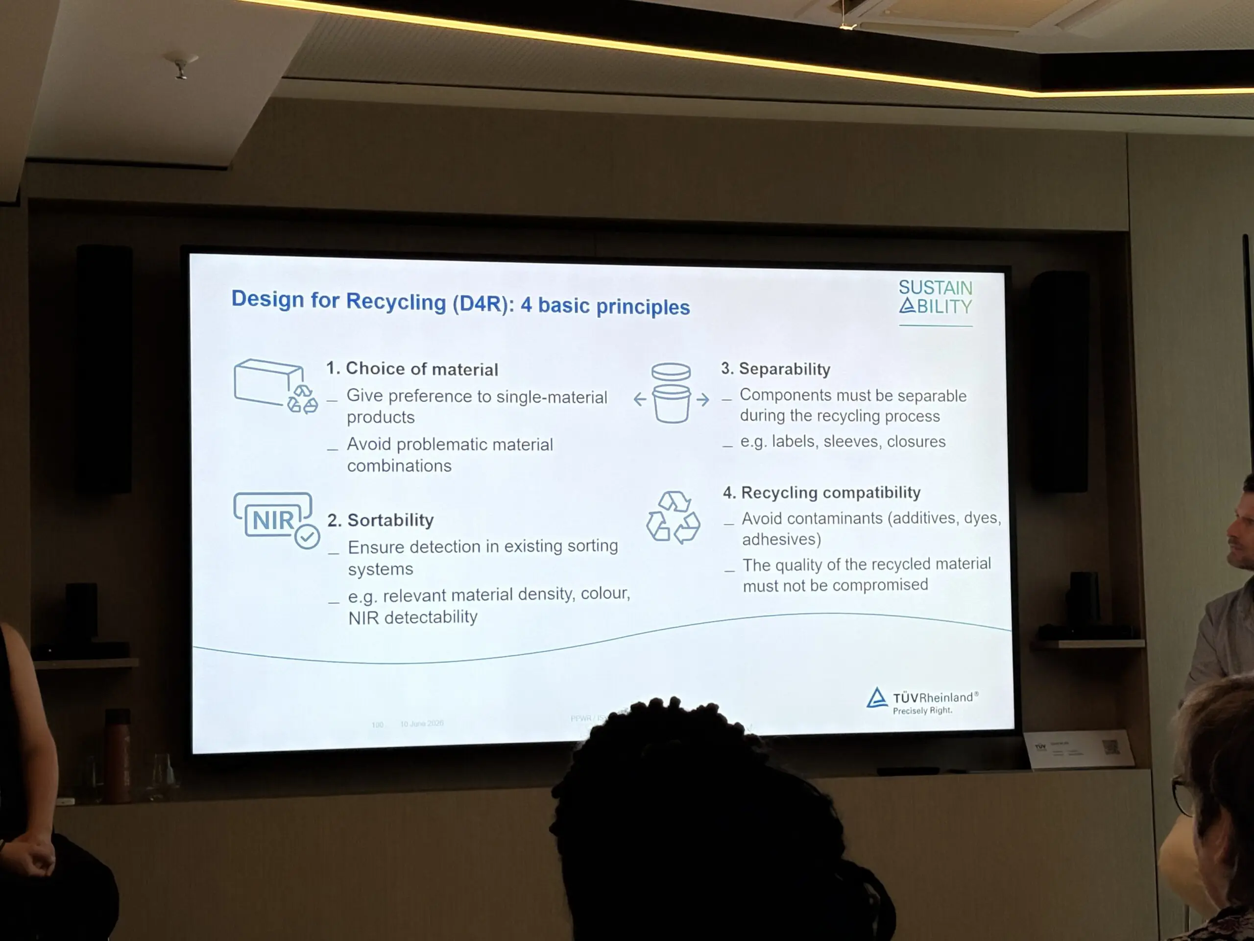 A presentation slide titled 'Design for Recycling (D4R): 4 basic principles' is shown on a screen. The slide details principles for sustainable product design, including choice of material, sortability, separability, and recycling compatibility. The TÜV Rheinland logo is visible at the bottom right.