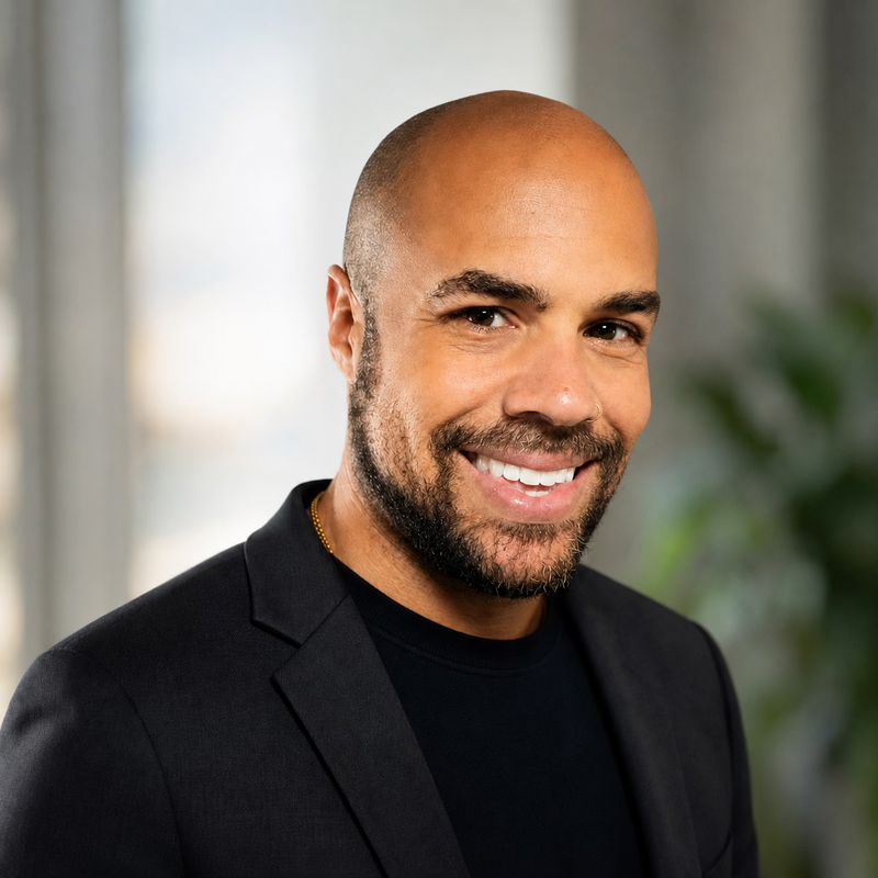 Headshot of a smiling man with a beard, wearing a black blazer.