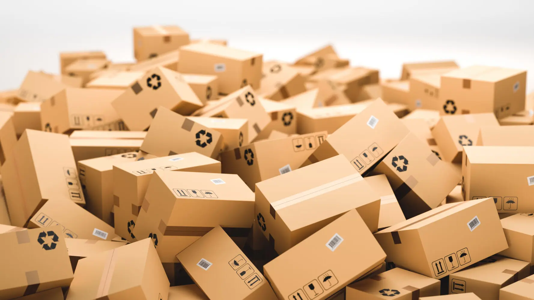 A large, overflowing pile of light brown cardboard boxes with various shipping and recycling symbols, and barcodes.