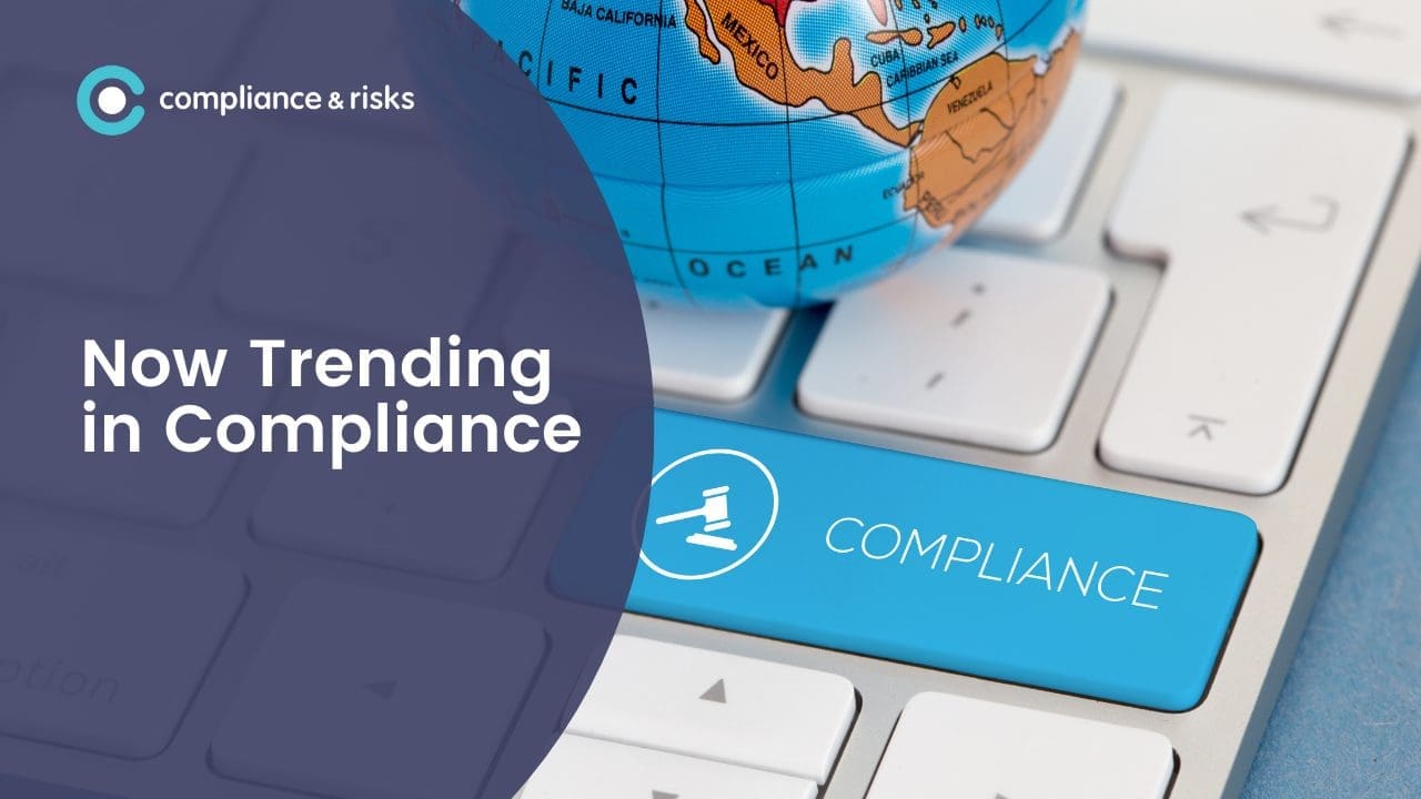 A computer keyboard with a globe and a blue key labeled 'COMPLIANCE' with a gavel icon. Text reads 'Now Trending in Compliance'.