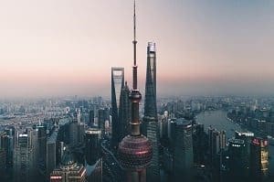 Aerial view of Shanghai skyline with Oriental Pearl TV Tower, Shanghai Tower, and Shanghai World Financial Center at dusk.