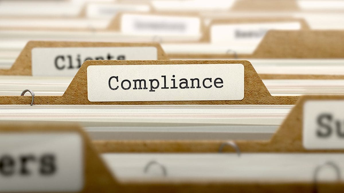 A close-up of file folders, with the central tab clearly labeled 'Compliance'. Other visible partial labels include 'Clients' and 'Su'.