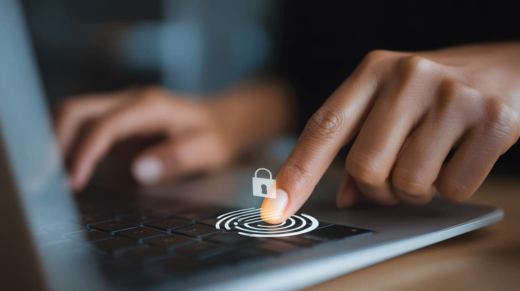A hand's index finger touches a laptop touchpad, with a digital fingerprint and padlock icon overlaid, symbolizing biometric security.