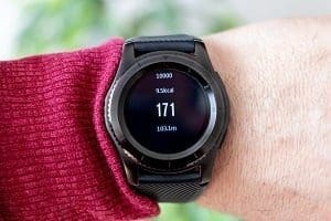 Close-up of a black smartwatch on a wrist, displaying '171' prominently, along with '10000', '1500kcal', and '10.0km' on its screen.