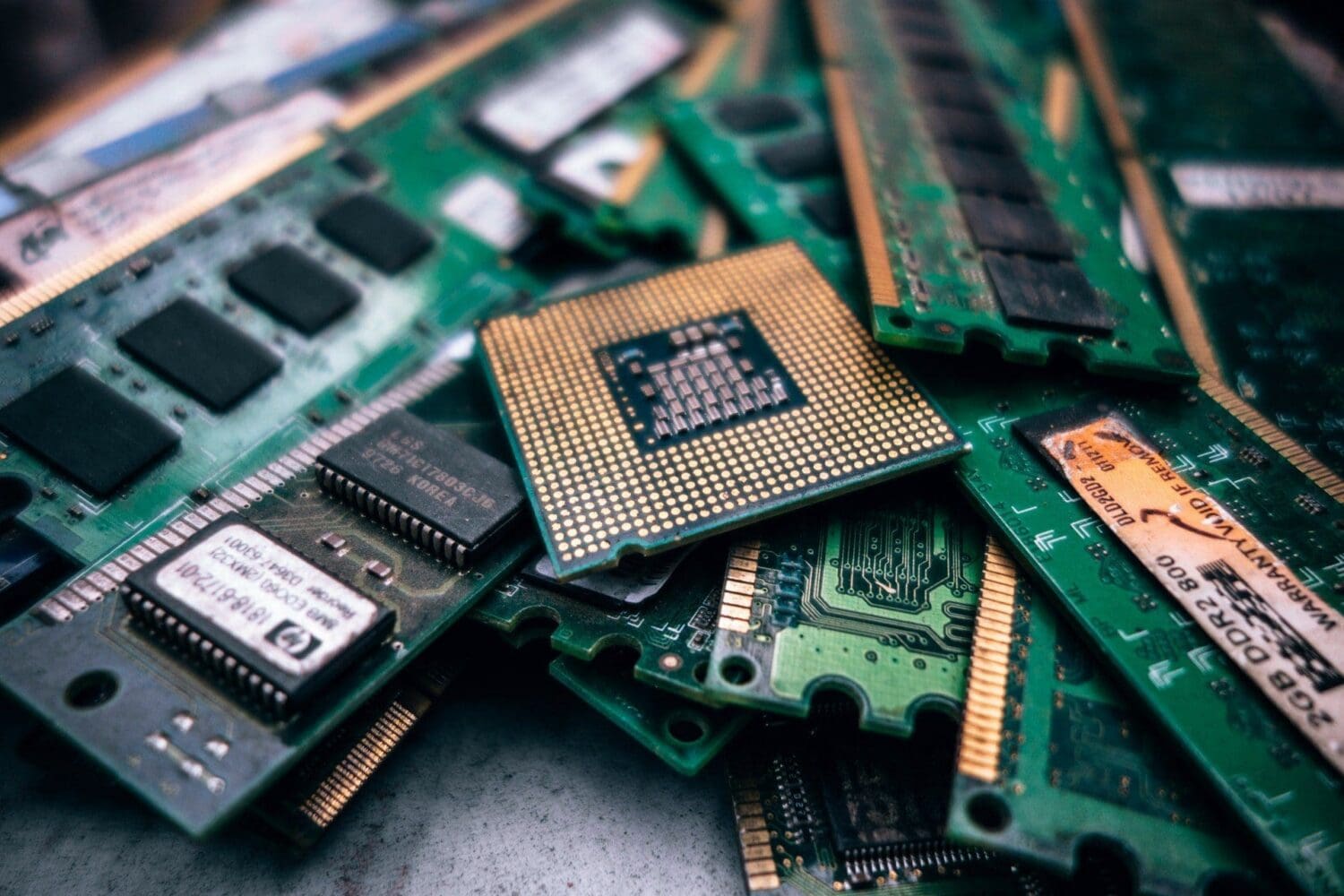 A pile of green computer components, including a central CPU with gold pins and several RAM sticks with black chips and gold contacts.