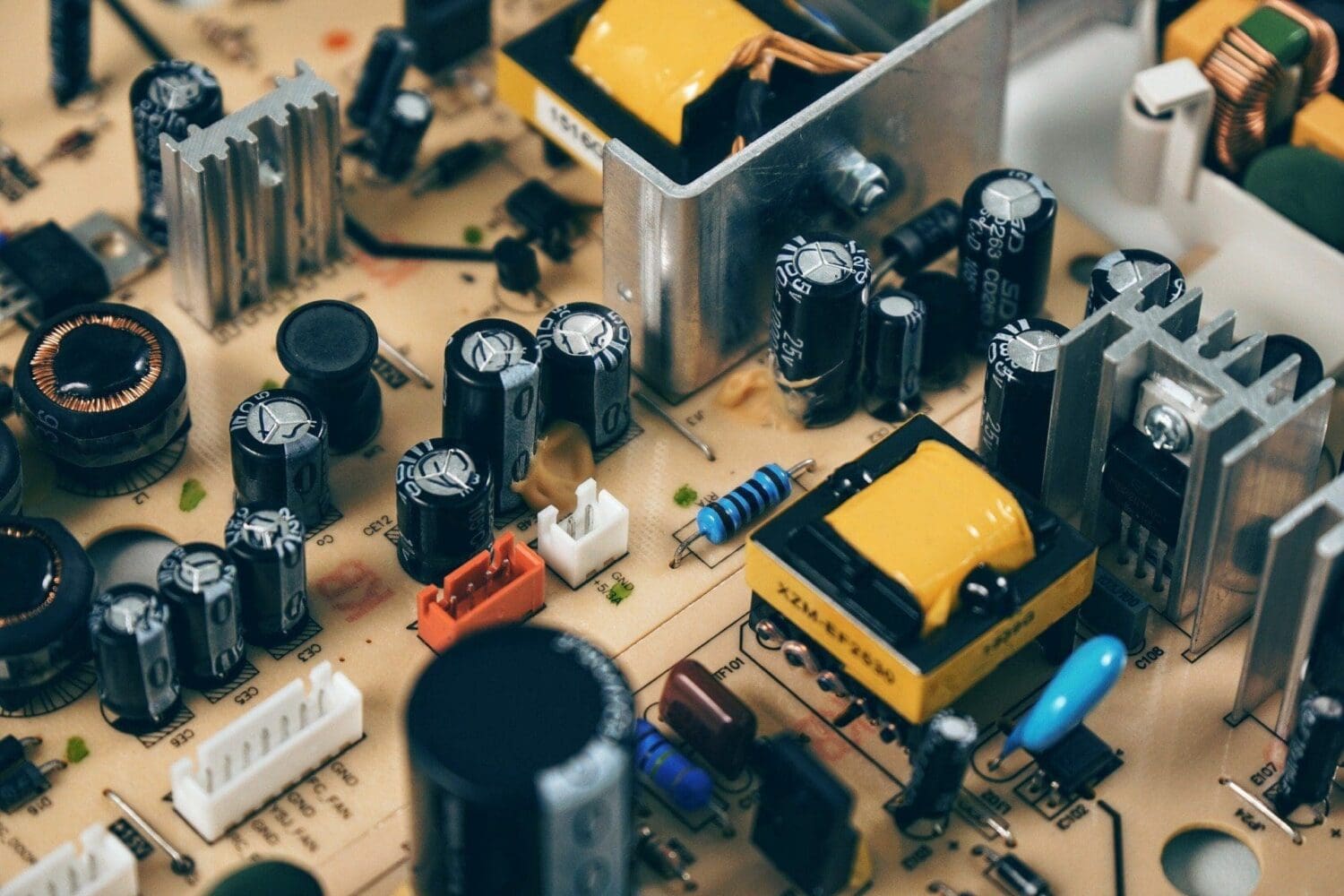 Close-up of an electronic circuit board with various components including capacitors, inductors, resistors, and heat sinks.