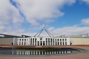 Front view of Parliament House, Canberra, with a tall flagpole and a circular reflecting pool.