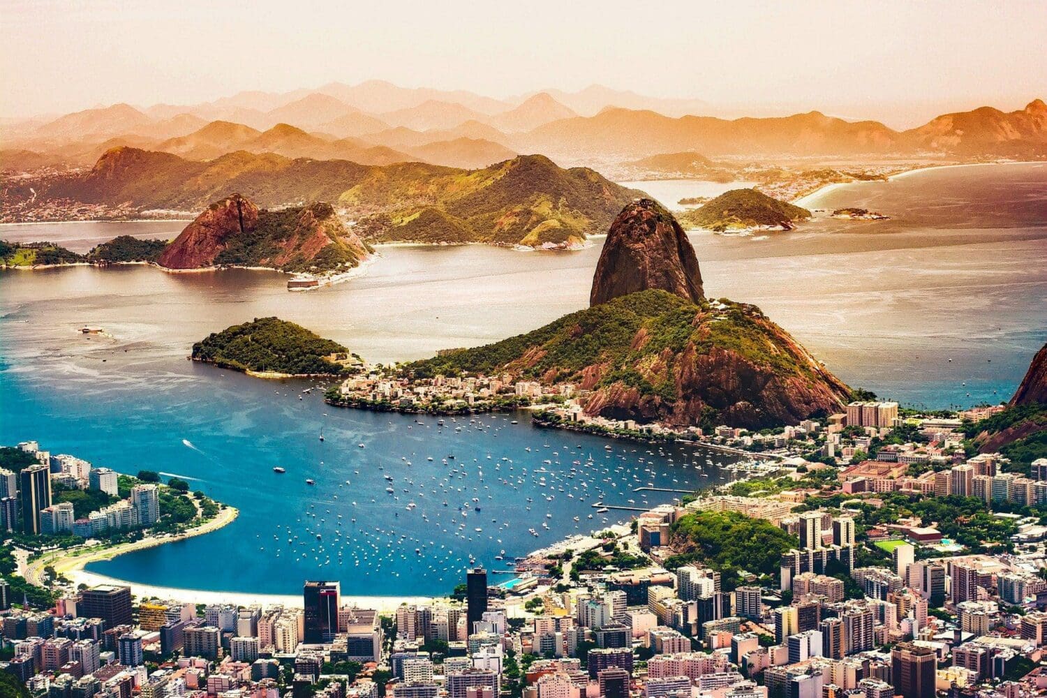 Aerial view of Rio de Janeiro with Sugarloaf Mountain, Guanabara Bay, and a dense cityscape.