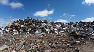 A large, towering pile of mixed scrap metal and debris under a blue sky with white clouds.