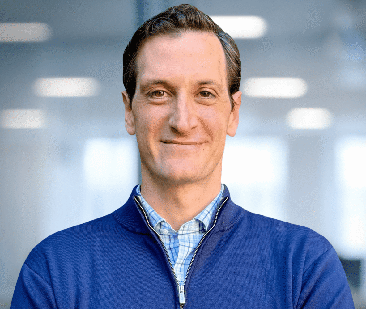 Portrait of a smiling man in a blue quarter-zip shirt.